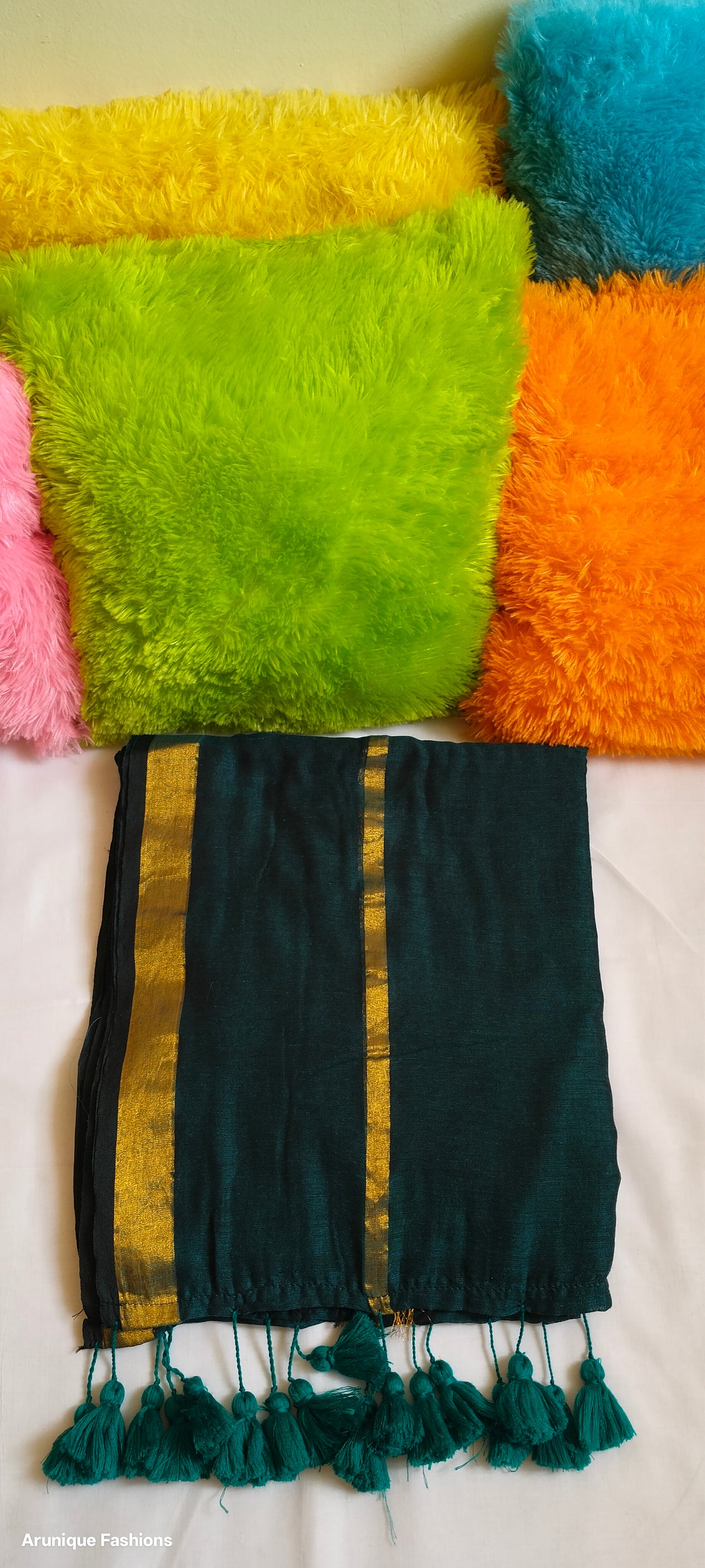 Close-up view of emerald green double zari saree showing dual golden zari borders and tasseled pallu with pillow for enhancement