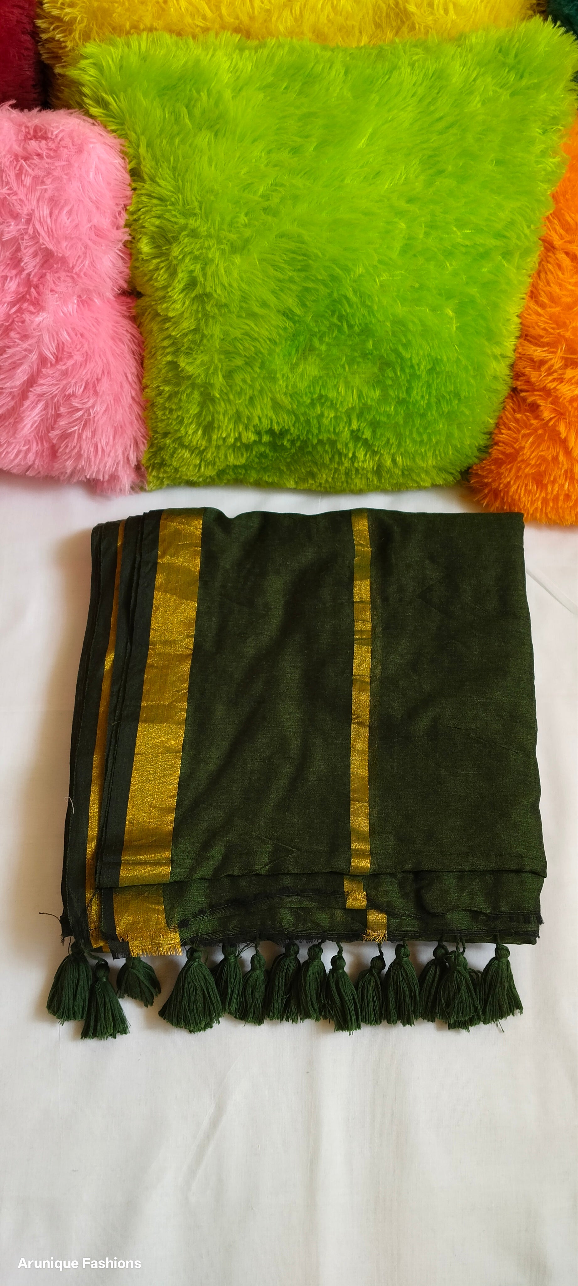 Dark green double zari mul cotton saree with golden borders and hand-tied tassels displayed folded
