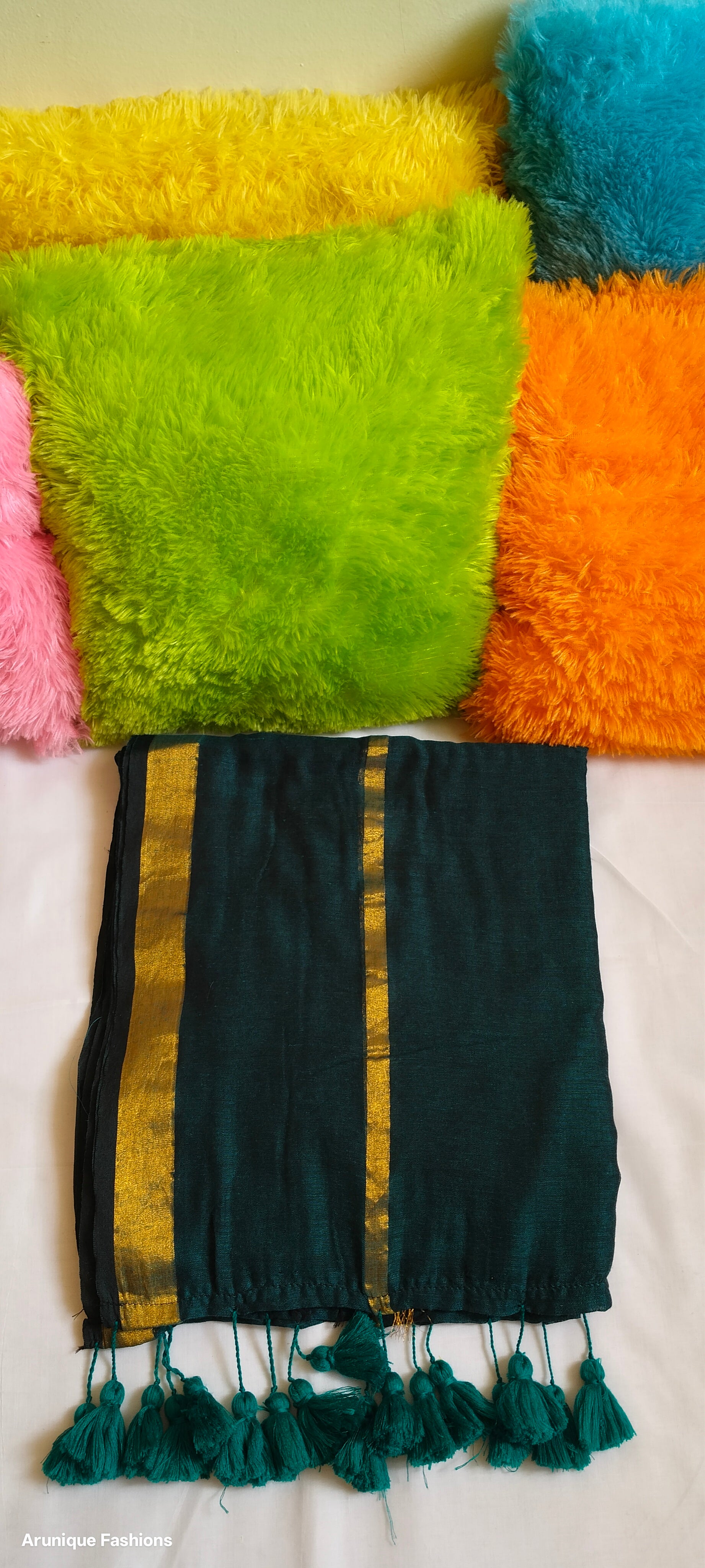 Close-up view of emerald green double zari saree showing dual golden zari borders and tasseled pallu with pillow for enhancement