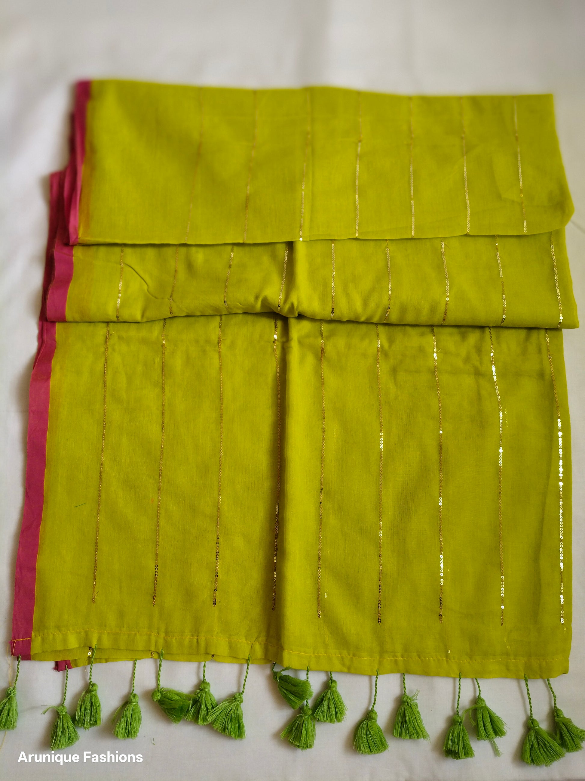 Trendy lime yellow sequin mul cotton saree - folded view showing pink border and green tassels