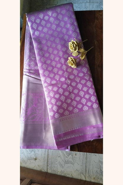Lavender brocade semi-silk saree displayed on wooden table