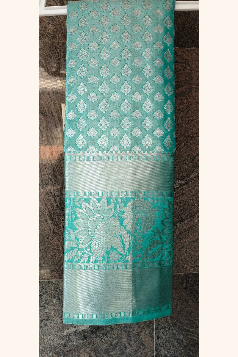 Mint green brocade saree on hanger showing wide silver tissue border detail