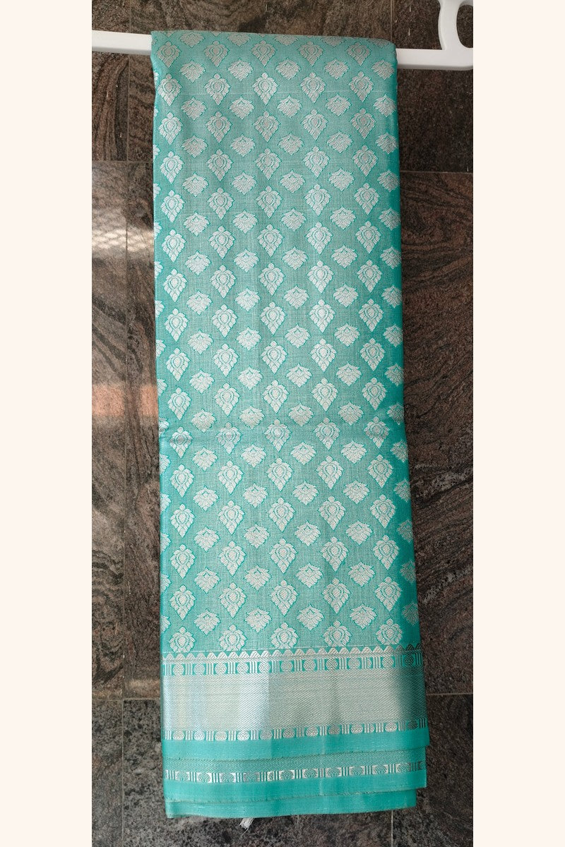 Mint green brocade saree on hanger showing short silver tissue border