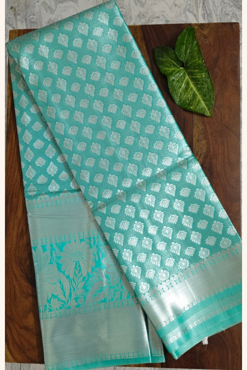 Mint green brocade semi-silk saree displayed on wooden table
