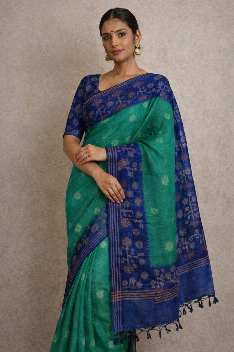 Indian woman model wearing Pure Tussar Silk Saree in emerald green with navy blue ikat border and pallu