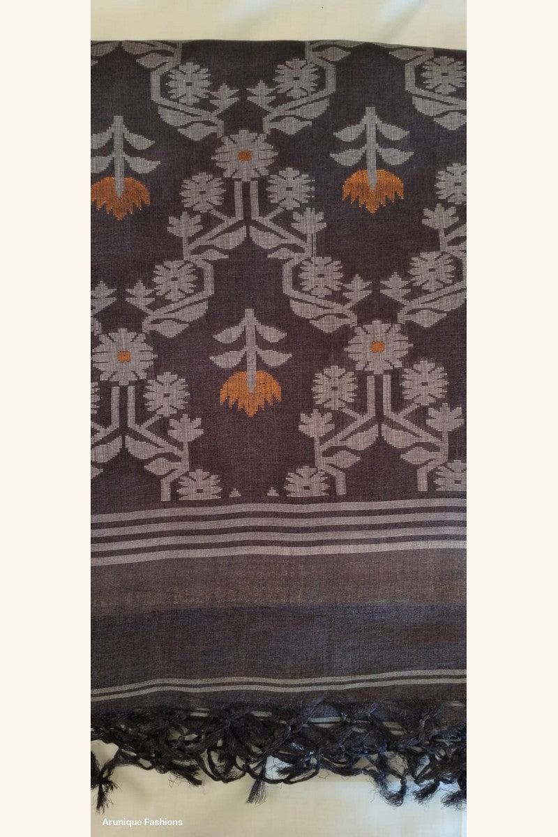 Close-up of charcoal black ikat pallu of Pure Tussar Silk Saree with dense lotus floral weave in silver-grey and burnt orange with black tassels
