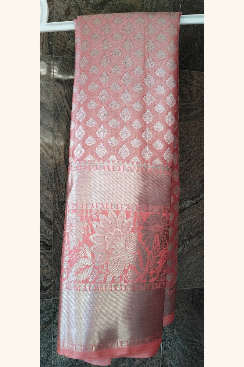 Rose pink brocade saree on hanger showing wide silver tissue border detail