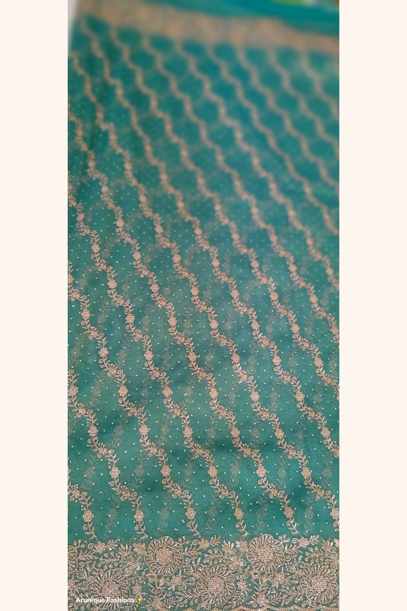 Teal green designer net saree - body close-up with diagonal gold zari floral vine rows and stone embellishments