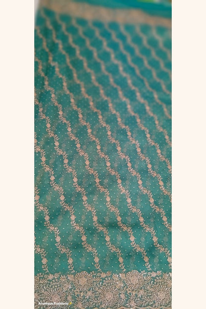 Teal green designer net saree - body close-up with diagonal gold zari floral vine rows and stone embellishments