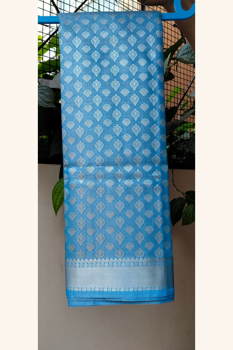 Sky blue brocade saree on hanger showing short silver tissue border
