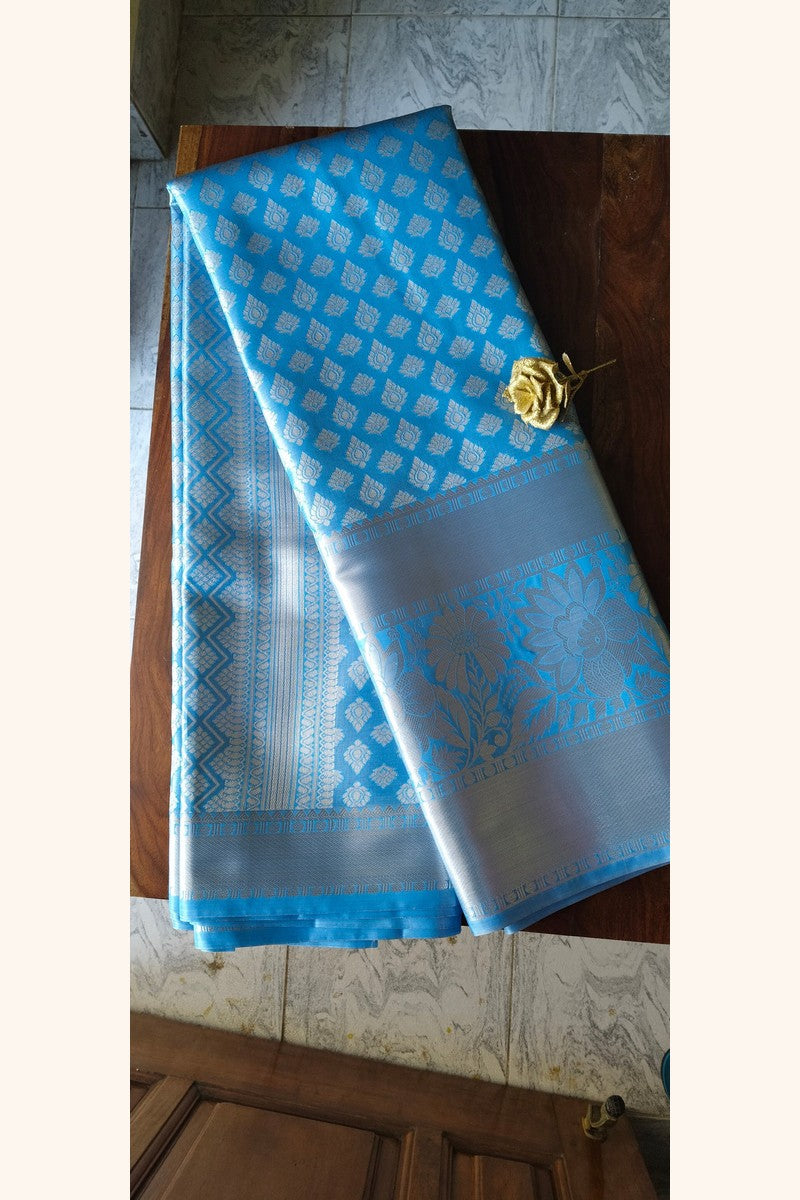 Sky blue brocade semi-silk saree displayed on wooden table